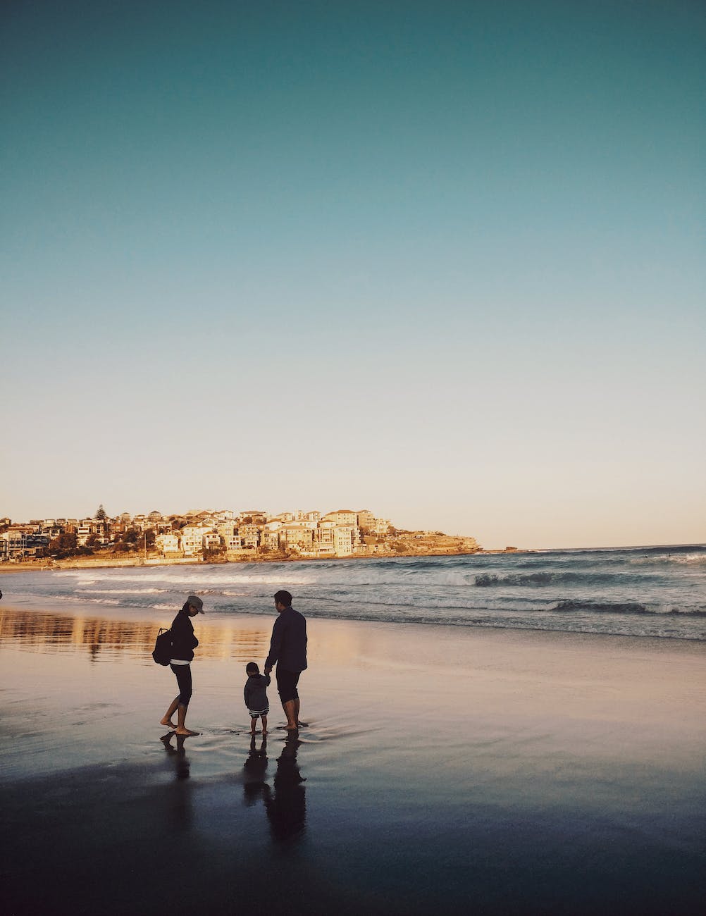 man and woman walking with boy in seashore