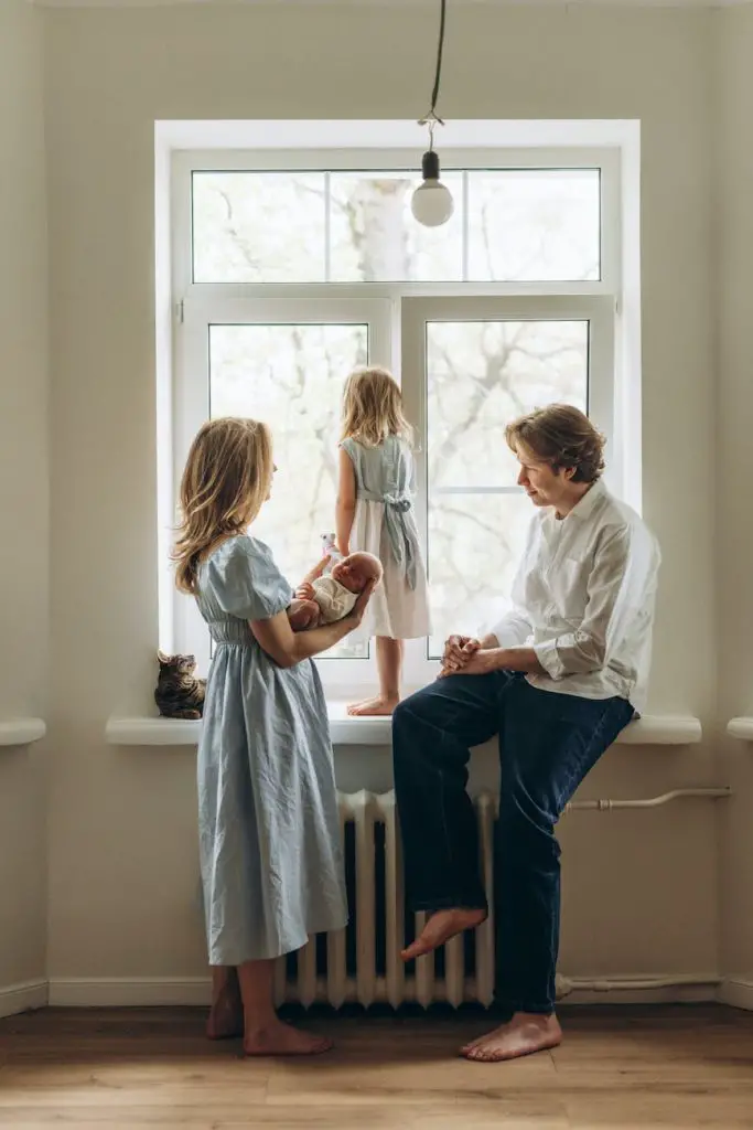 couple with kids sitting by windowsill