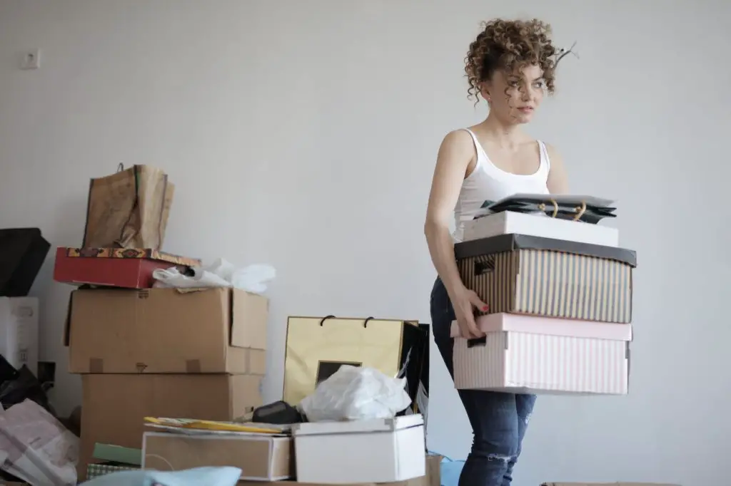 concentrated woman carrying stack of cardboard boxes for relocation